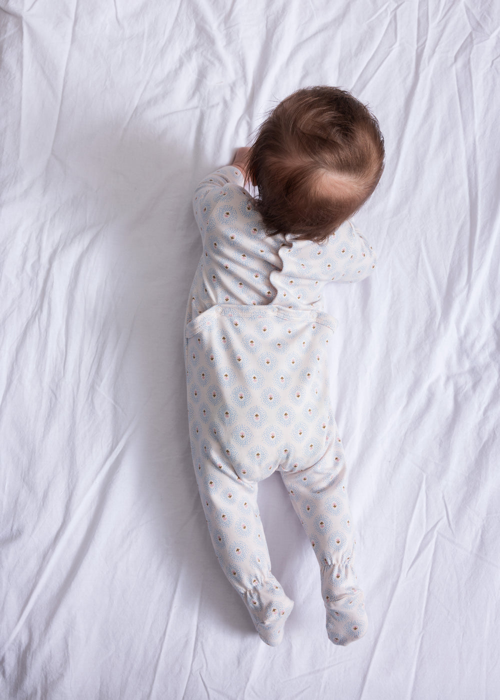 Heldragt til baby i hvid med små tulipanmønstre, båret på spædbarn