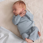 Baby i lyseblå ribstrikket bluse med lange ærmer og slå-om-facon