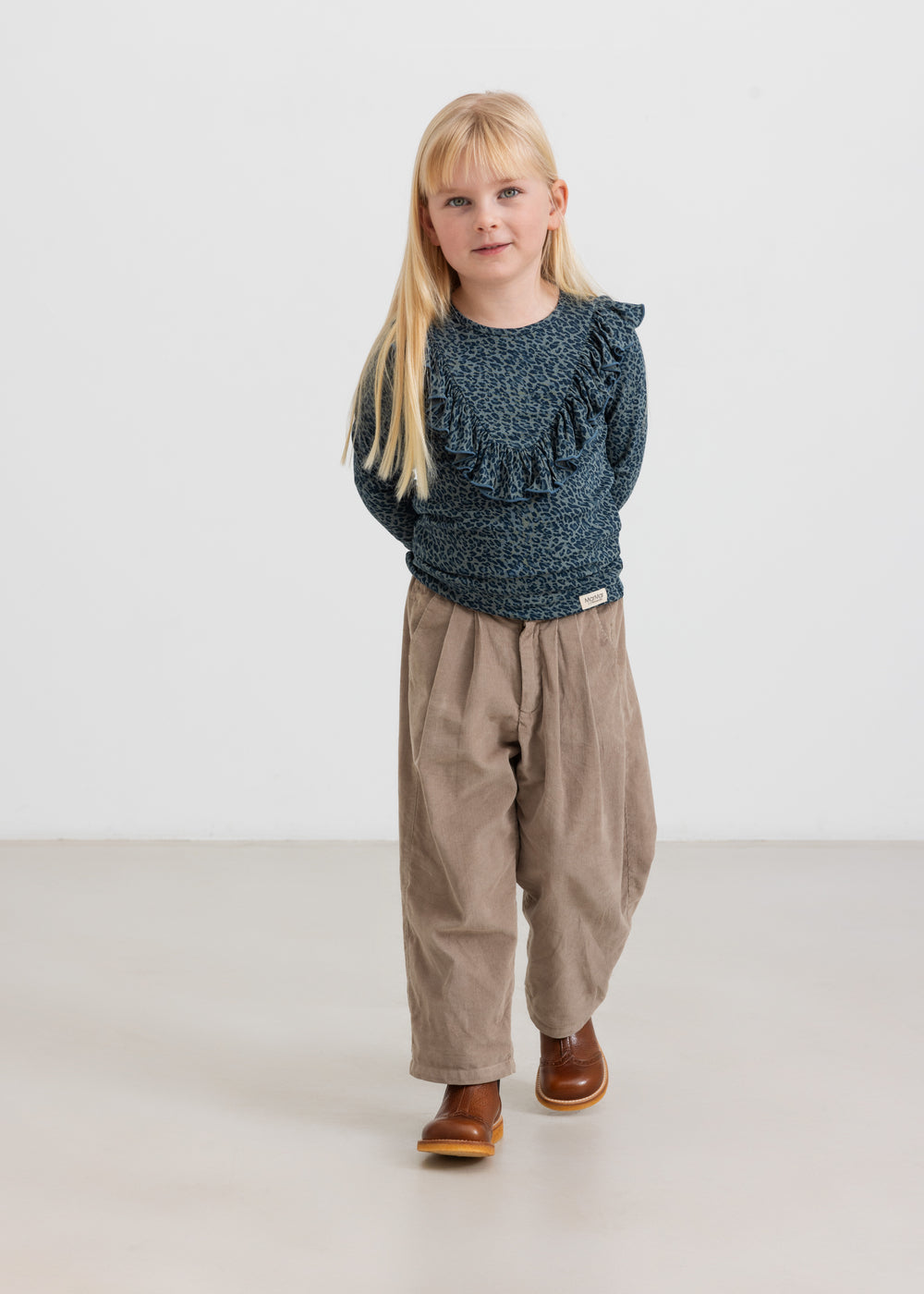 Pige iført beige babyfløjlssbukser og mørkeblå bluse