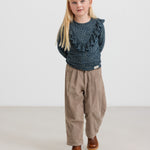 Pige iført beige babyfløjlssbukser og mørkeblå bluse