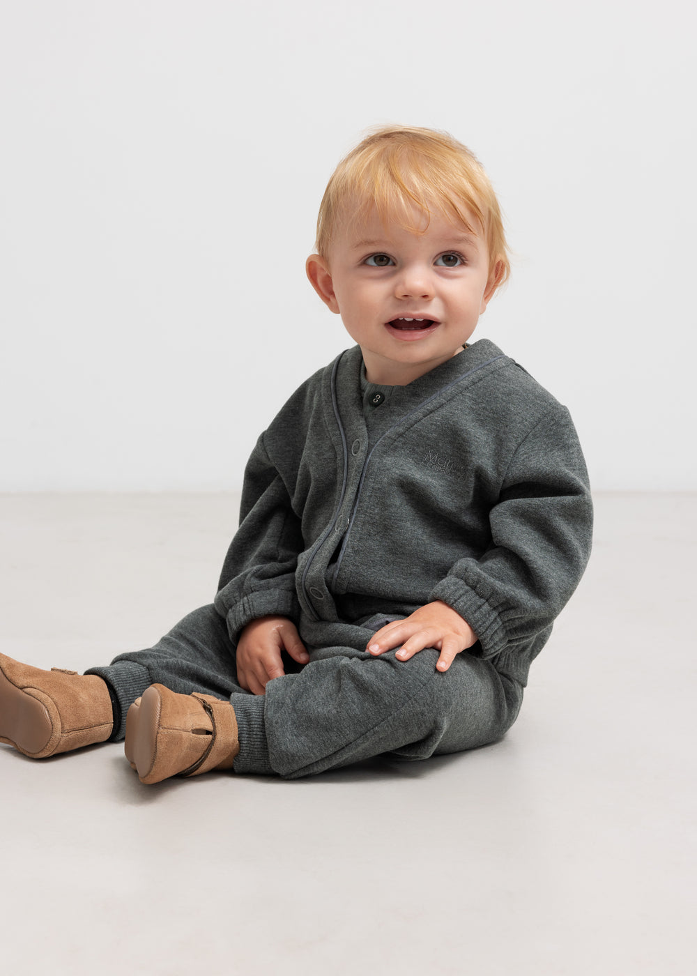 Meleret mørkegrøn babybluse på model med knaplukning foran og ribkanter