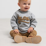 Barn iført brune ribstrikkede bukser og grå sweatshirt