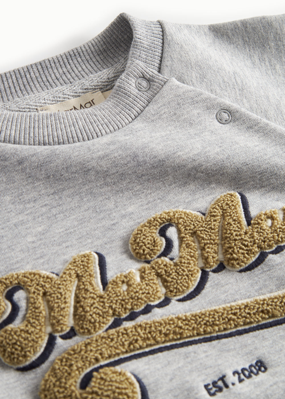 Detaljer af guld broderi på grå sweatshirt til børn
