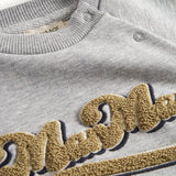 Detaljer af guld broderi på grå sweatshirt til børn