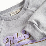 Nærbillede af broderi og ribkant på grå sweatshirt til børn