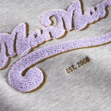 Detaljer af lilla og guld broderi på grå sweatshirt til børn