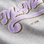 Nærbillede af lila broderet logo på grå sweatshirt til børn