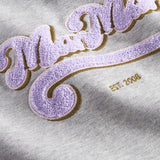 Nærbillede af lila broderet logo på grå sweatshirt til børn