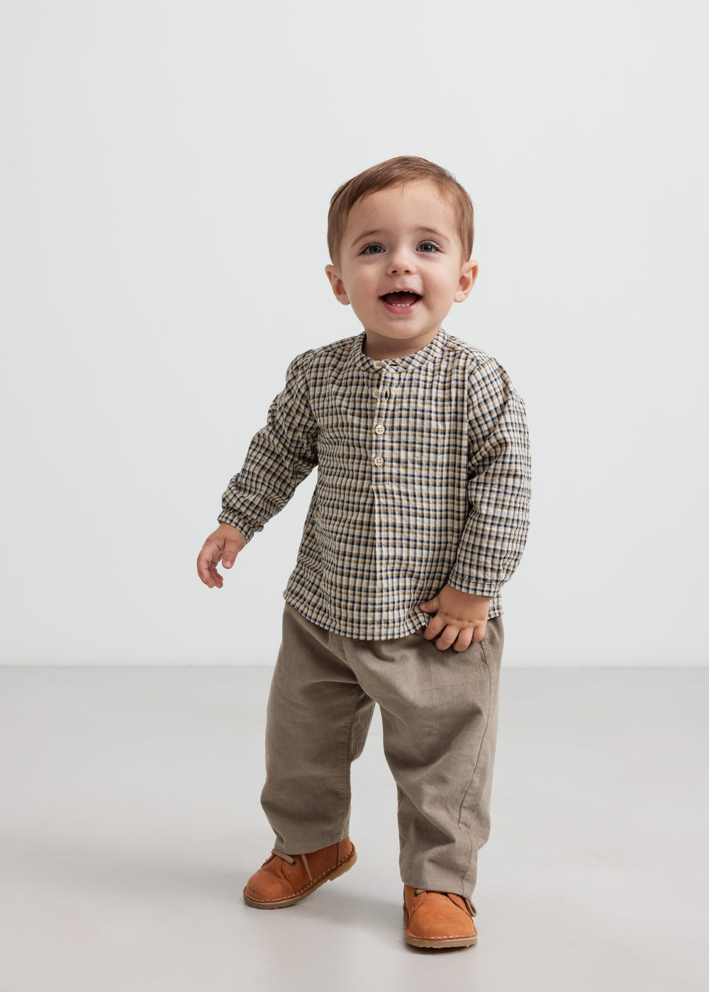 Baby iført beige babyfløjlssbukser og bluse