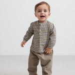 Baby iført beige babyfløjlssbukser og bluse