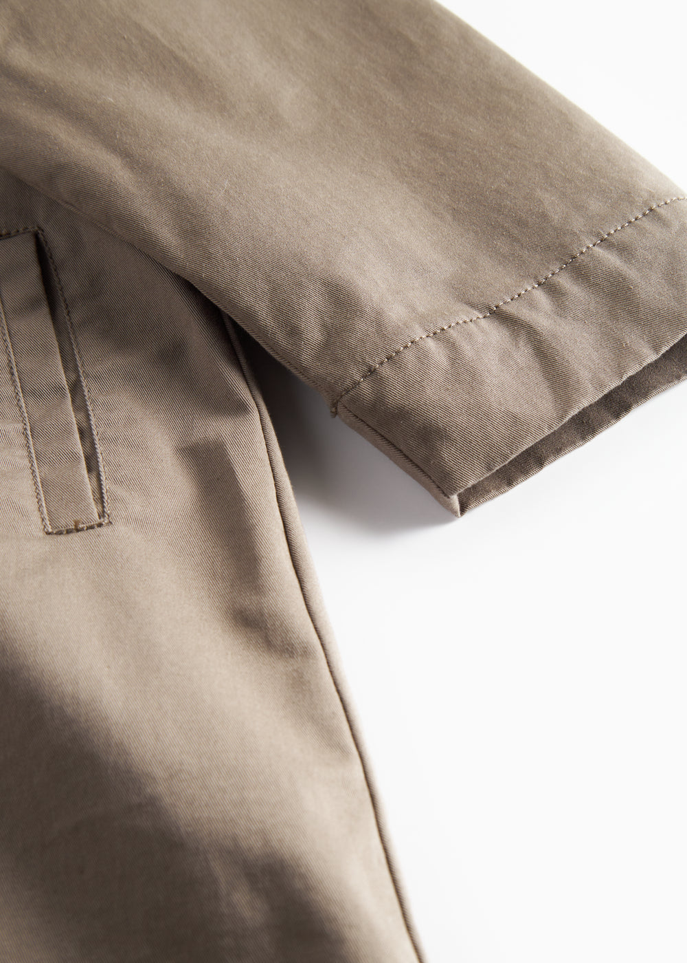 Detaljebillede af ærme og lommer på kaki chino frakke