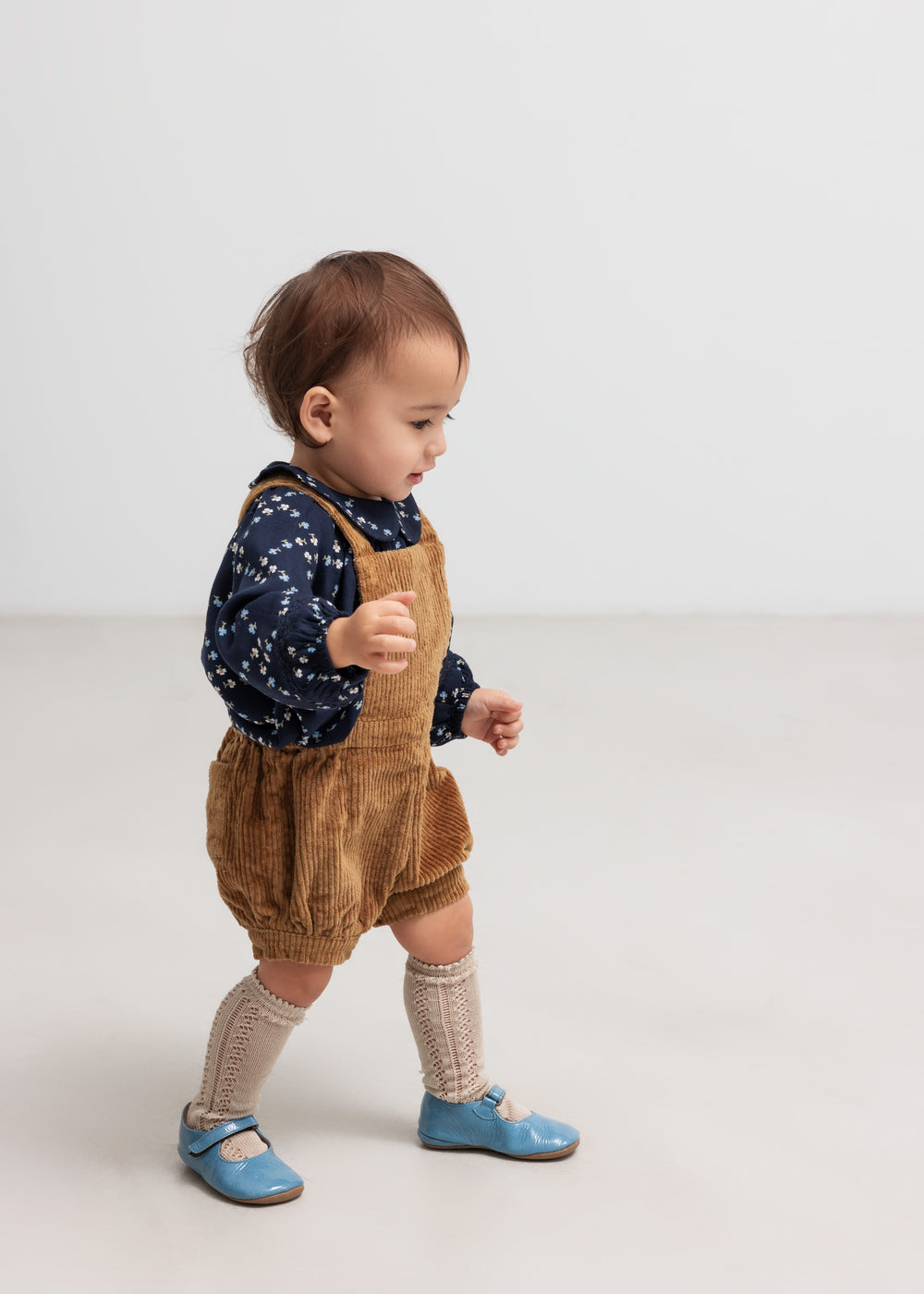 Baby iført mørkeblå blomstermønstret bluse og seleshorts.