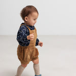 Baby iført mørkeblå blomstermønstret bluse og seleshorts.