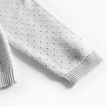 Detalje af ærme med hulmønster på grå strikbluse