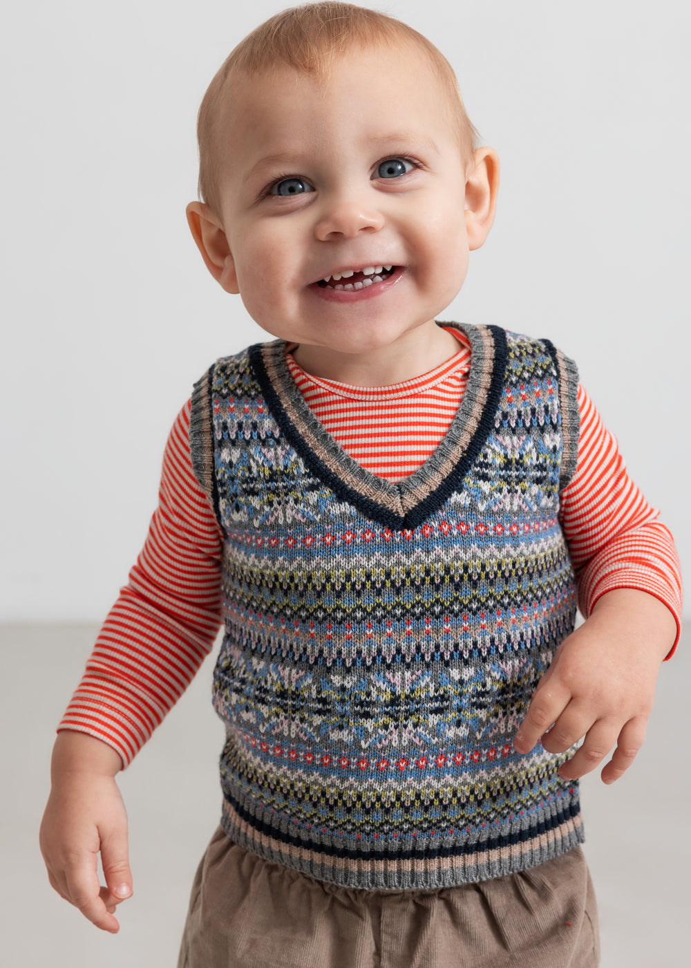 Baby med mønstret strikvest over stribet bluse