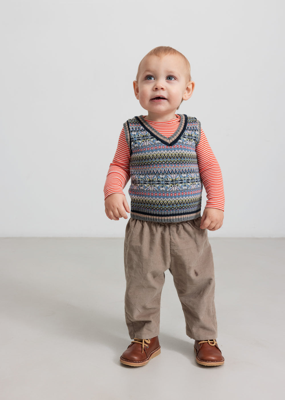 Baby med mønstret strikvest over stribet bluse