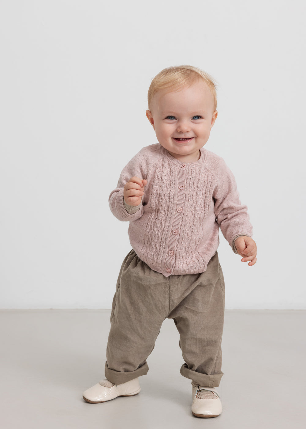 Barn i beige babyfløjlssbukser og lyserød trøje