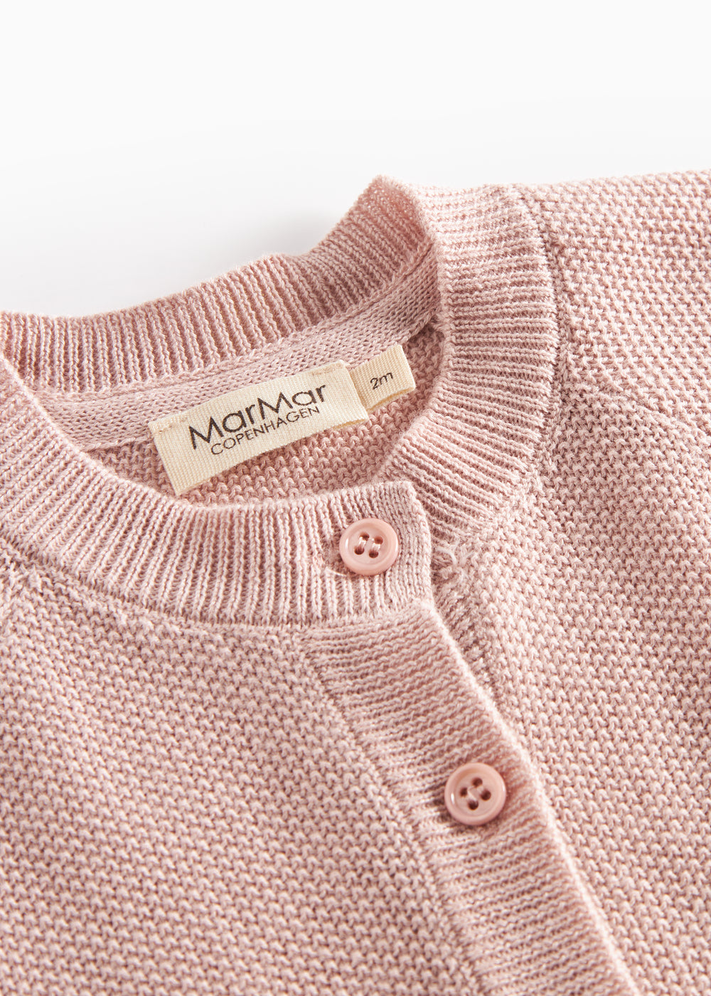 Nærbillede af knapper og halskant på lyserød strikket baby cardigan.