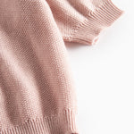 Nærbillede af ribkant ved ærme på lyserød strikket baby cardigan.