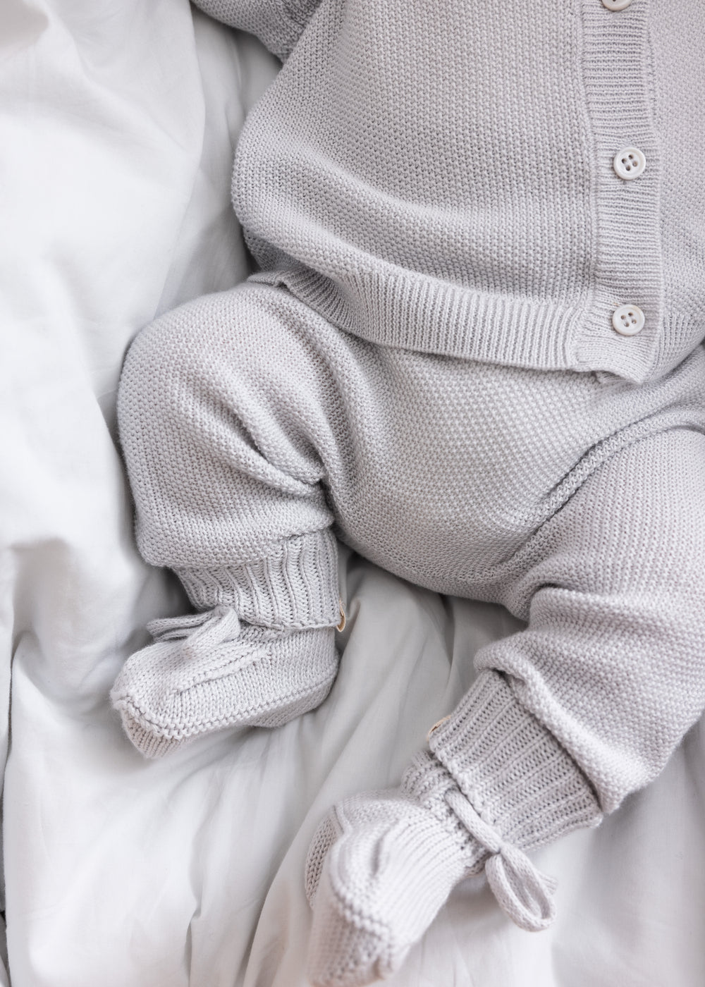 Detaljer af babyben i gråt strikket sæt med små strømper