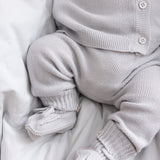 Detaljer af babyben i gråt strikket sæt med små strømper