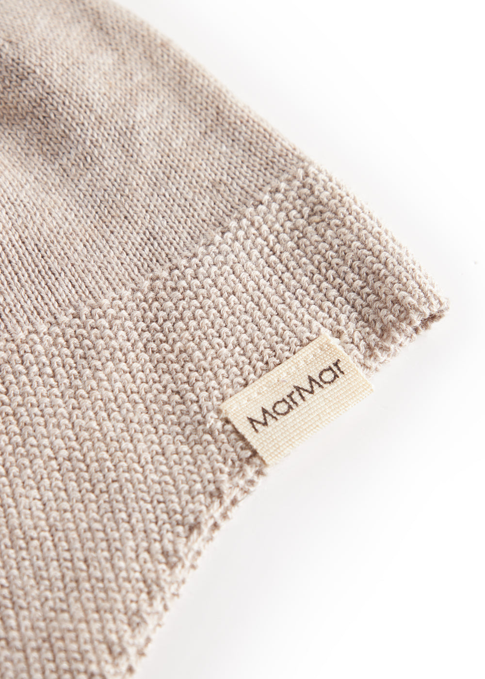 Detaljer af beige strikket babyhue med MarMar mærke
