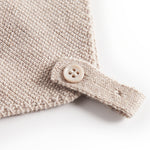 Nærbillede af knaplukning på beige strikket babyhue