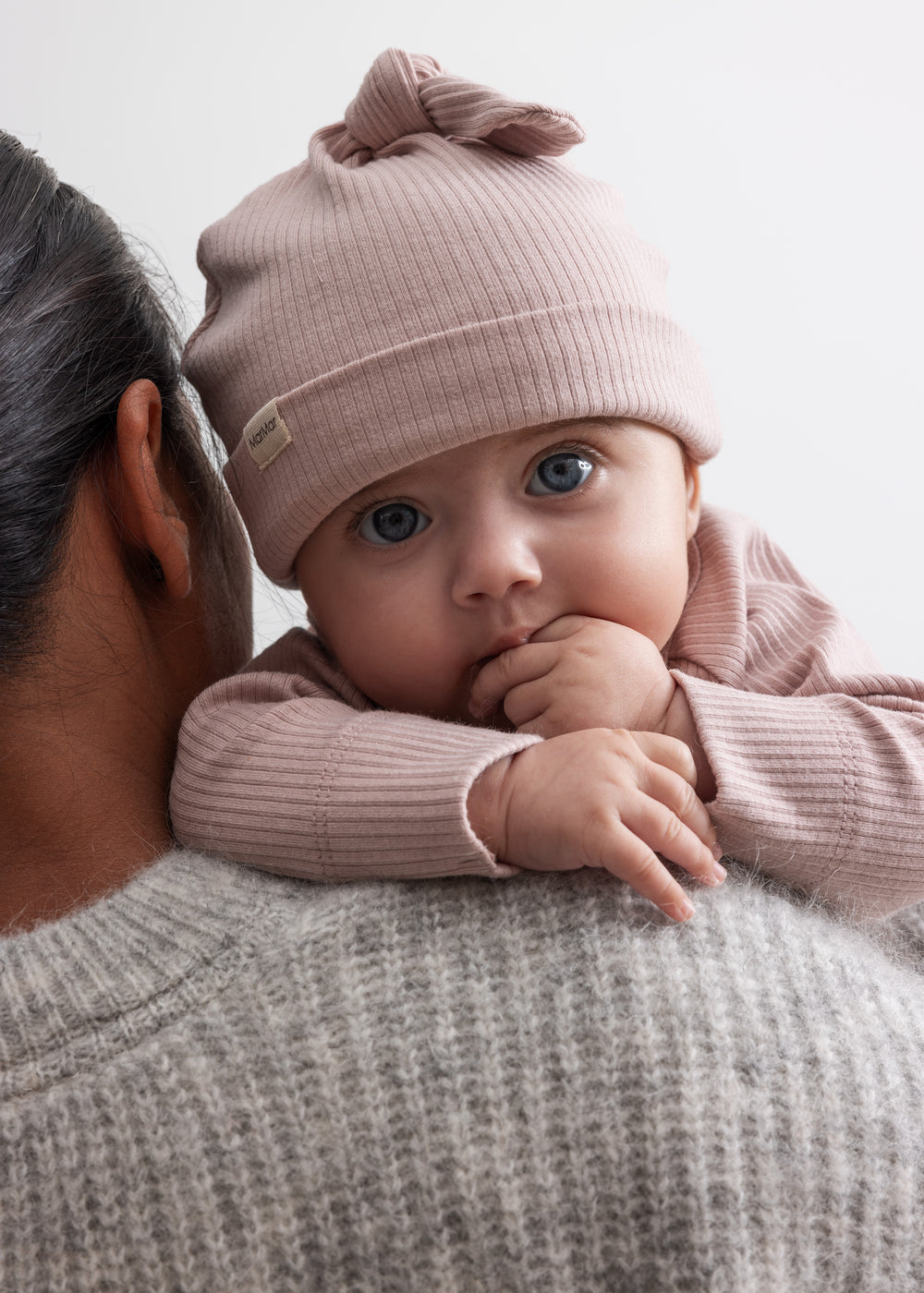 Baby med en lyserød hatt og en ribbet bluse