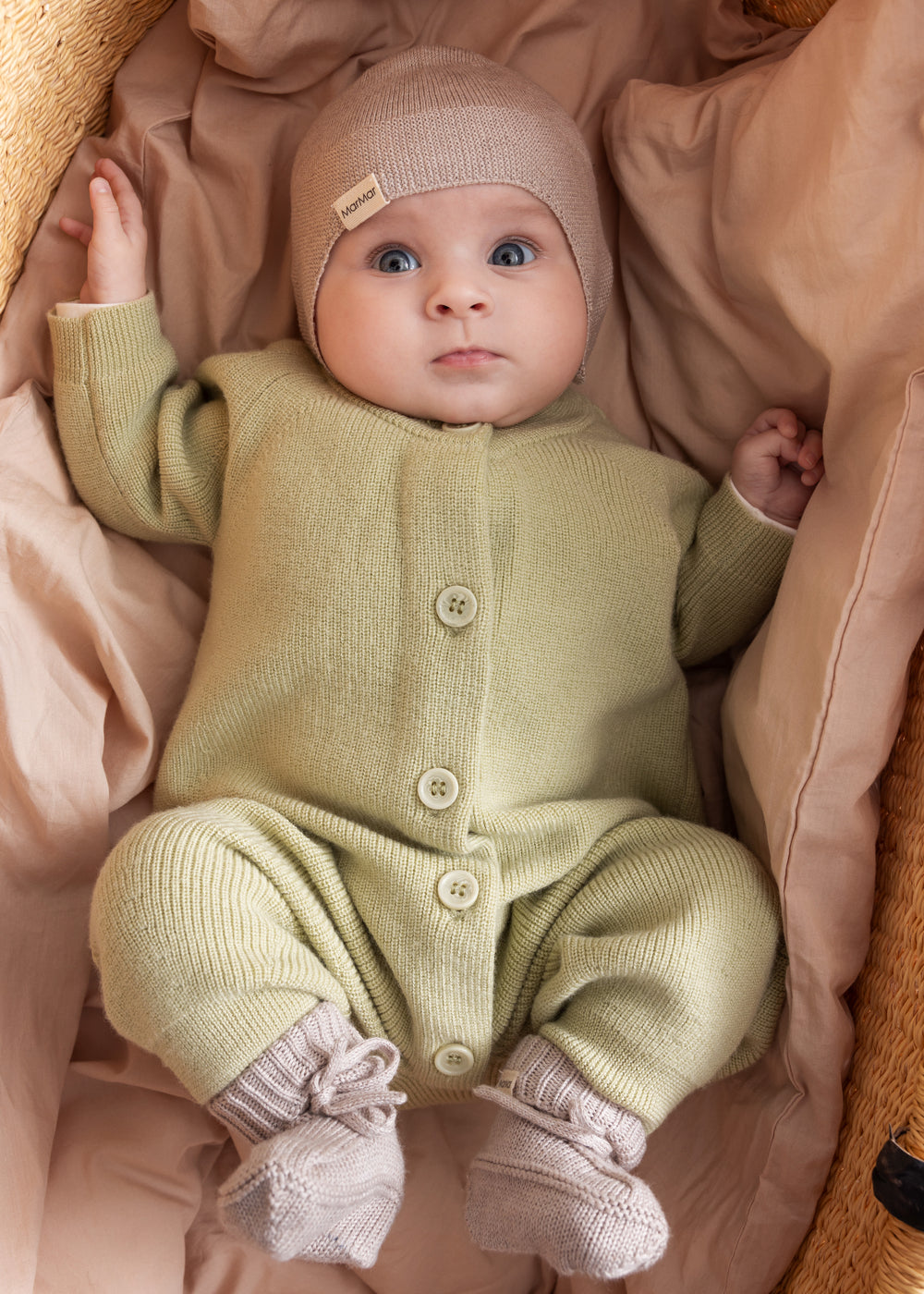 Baby iført blødt beige strikket holdtt med knapper foran