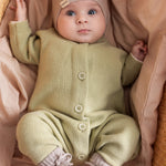 Baby iført blødt beige strikket holdtt med knapper foran
