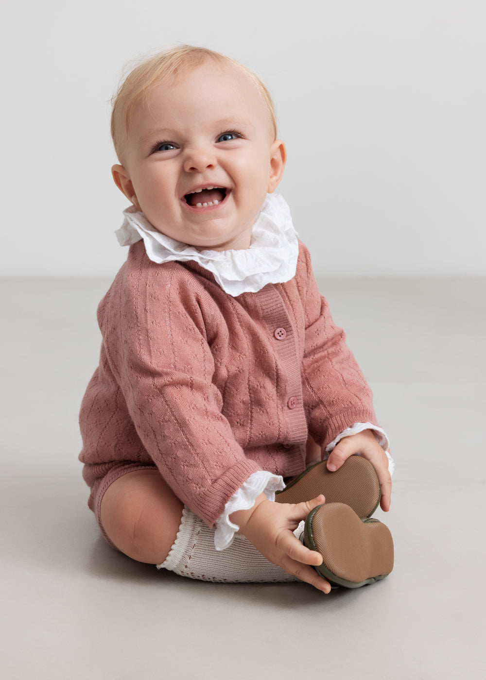 baby iført rosa strikket sæt med hvid flæsekrave
