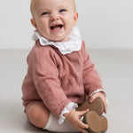 baby iført rosa strikket sæt med hvid flæsekrave