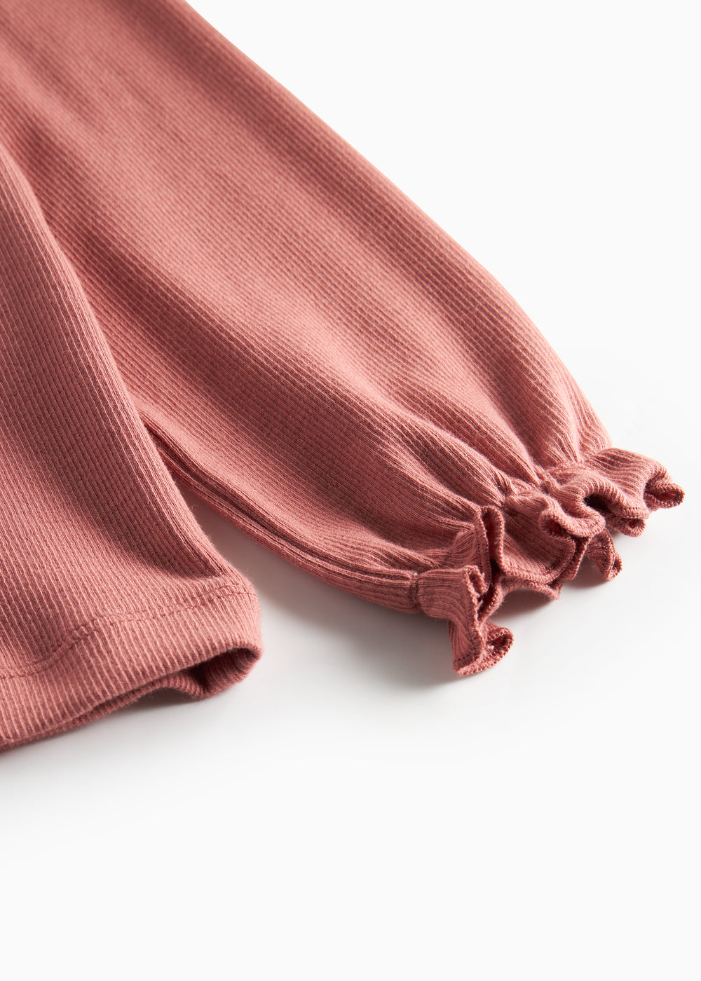 Detalje af ærmekant med små flæser på støvet rosa bluse til børn