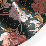 Nærbillede af mørkegrønt glansstof med blomsterprint og gyldne detaljer på festkjole til børn