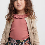 Pige iført beige cardigan med guldglimmer, rosa bluse og blomstretmønstret festnederdel til børn