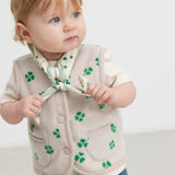 Baby iført beige tørklæde med grønt kløverprint og matchende fleece vest