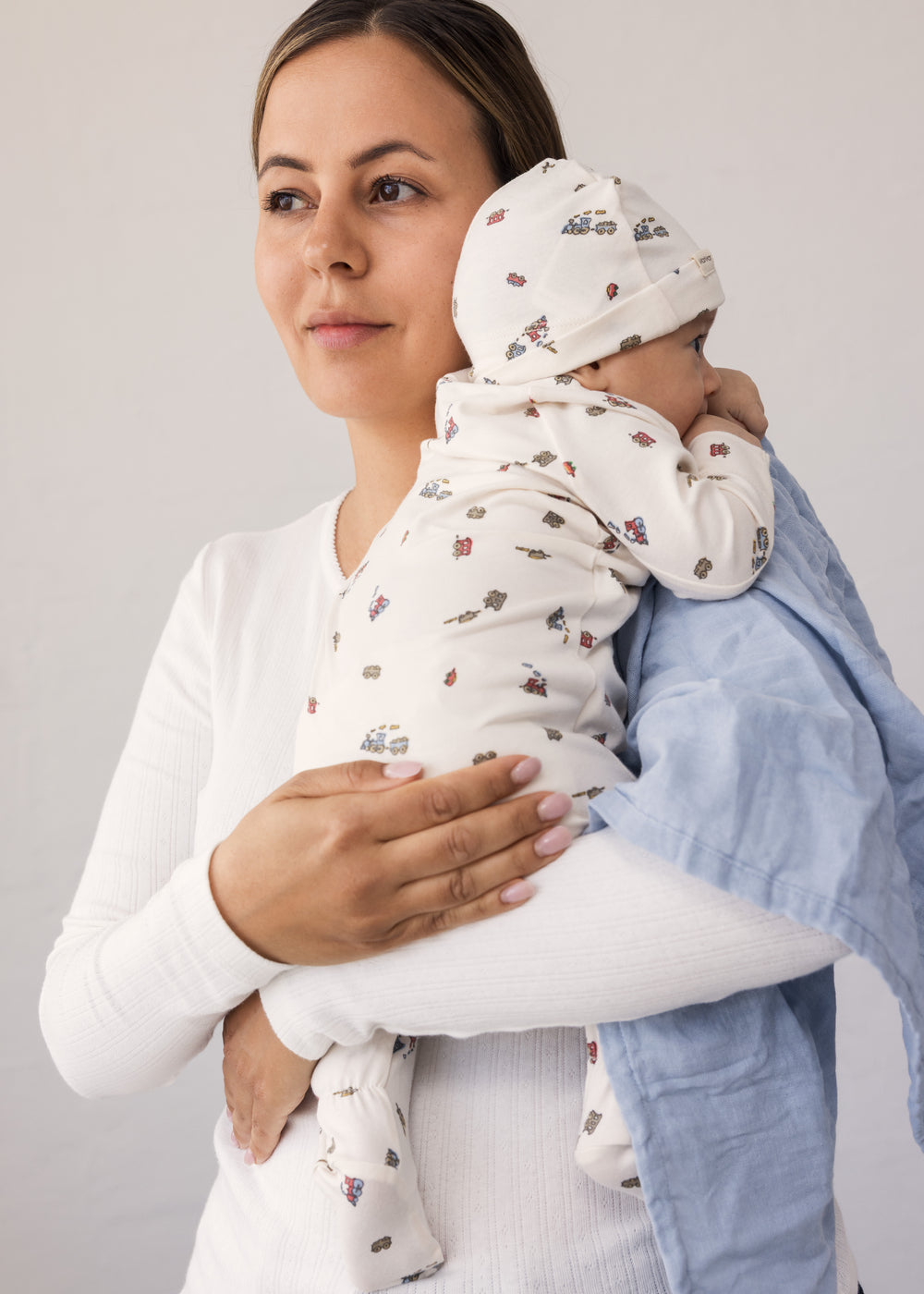 Baby holdt af kvinde med stofble over skulderen