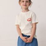Barn iført råhvid T-shirt med Mumin-print og denimshorts