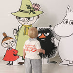 Baby iført råhvid T-shirt med Mumin-print og lyse bukser sammen med Moomin figurer