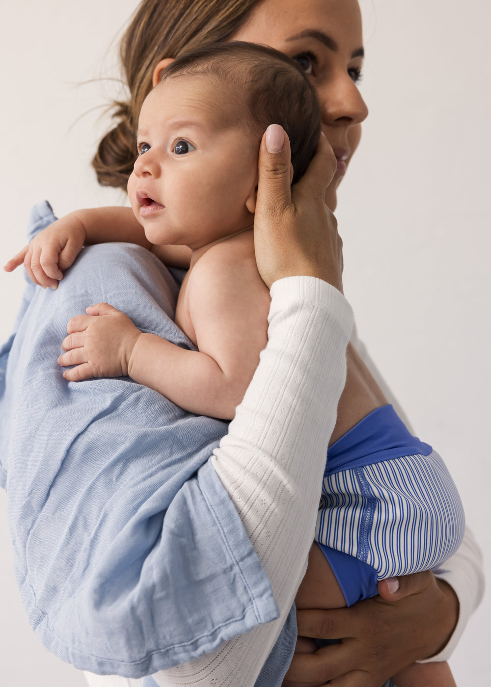 Baby holdt af kvinde med stofble omkring kroppen
