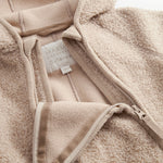 Beige teddyfleece heldragt med lynlås, synlig indvendig mærkning og snor