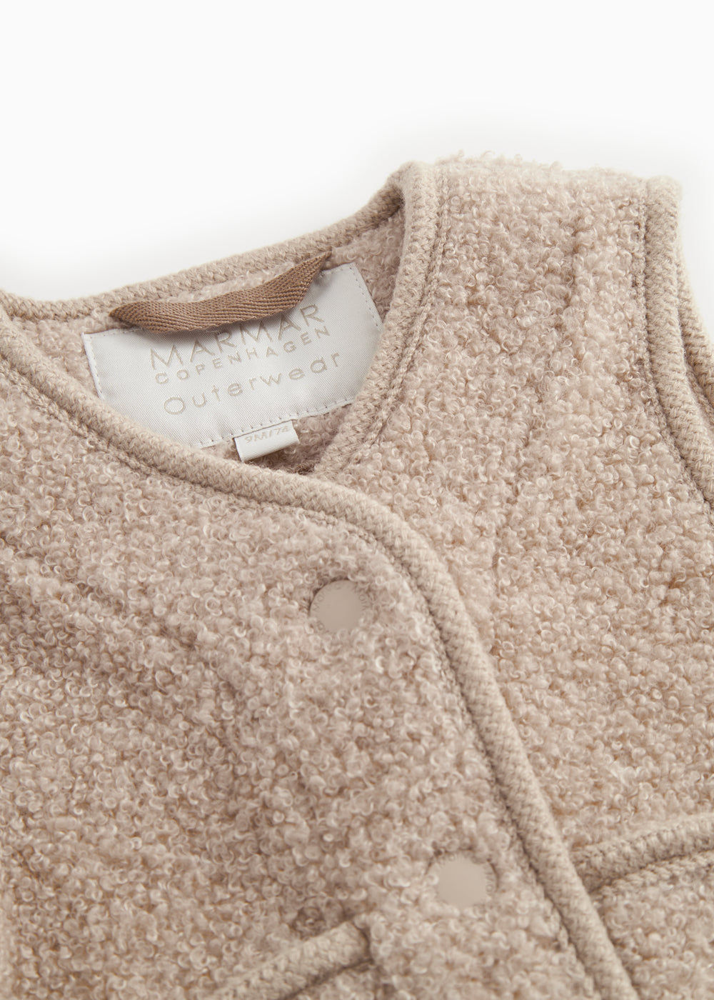 Beige teddy-vest med krave, trykknapper og synligt indvendigt mærkelabel
