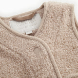 Beige teddy-vest med krave, trykknapper og synligt indvendigt mærkelabel