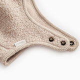 Teddyhue i mudret beige med trykknapper ved nederkant og rund krave