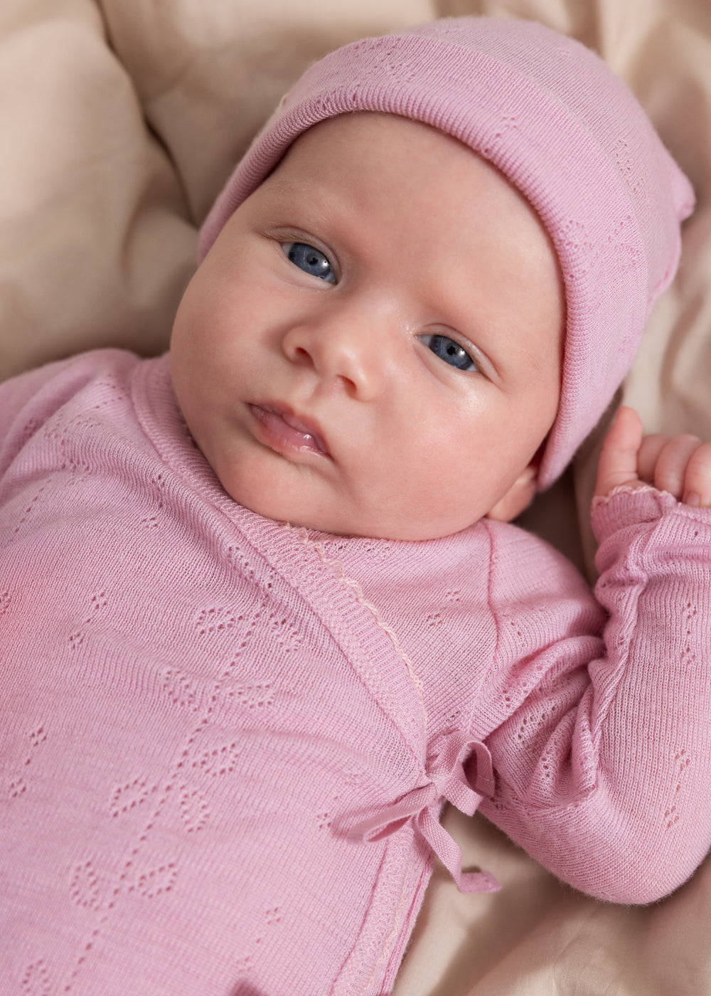 Lyserød strikhue på baby med rund top og fint strikket mønster