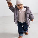 Lyserød babycardigan med knaplukning, synlig under grå vinterjakke.