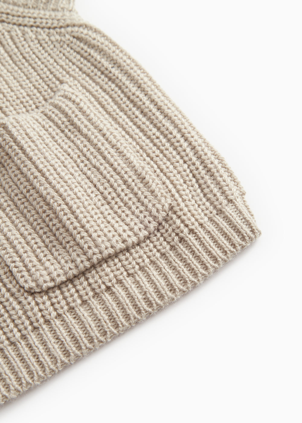 Taju strikvest i barely beige, ribstrikket kant og tæt struktur ved sømmen