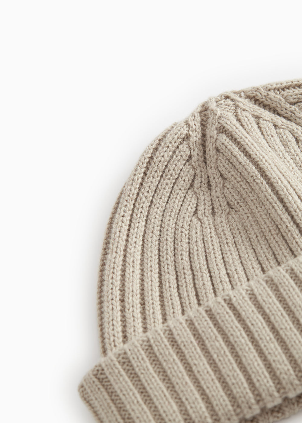 Detalje af barely beige strikhue med lodrette ribber og foldet kant.