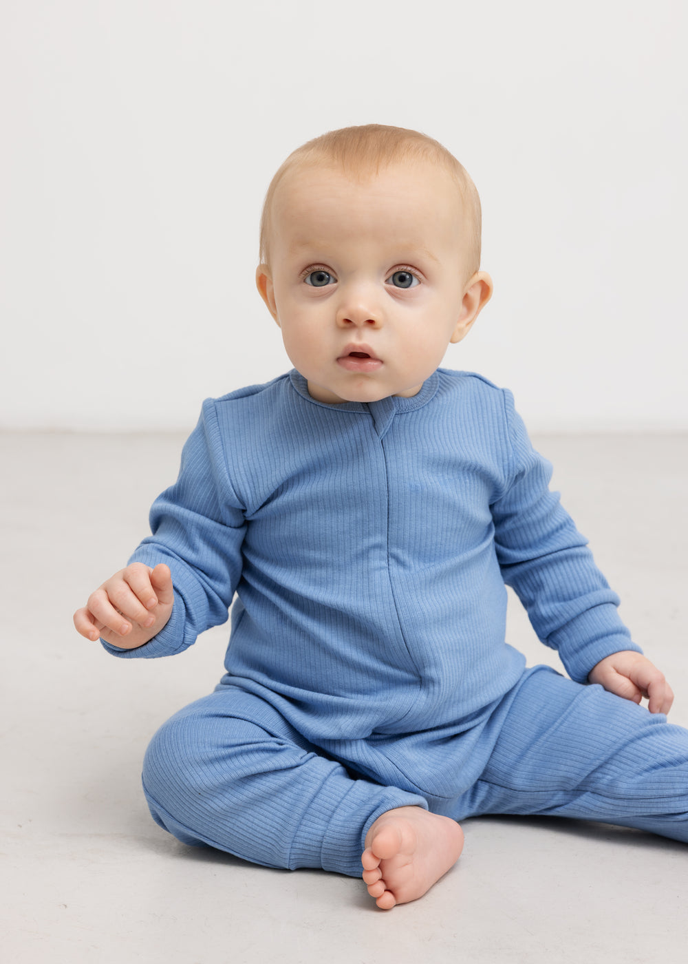 Lyseblå heldragt på baby med lynlås foran og lange ærmer, ribbet stof