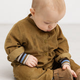 Baby set forfra i brun heldragt med stribede manchetter og ribkant ved ærmer.